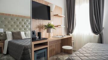 Habitación de hotel con cama, escritorio con cafetera, televisión y una planta.