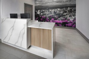 A reception desk with a cityscape mural, a door, and a tiled floor. - La Quinta Inn & Suites by Wyndham Downtown Asheville (Asheville)