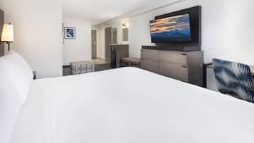 A hotel room with a large bed, a flat-screen TV mounted on the wall, a desk, and a chair.