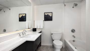 A modern bathroom with a large mirror, a sink, a toilet, and a bathtub.