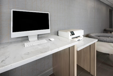 A modern workspace with a desktop computer, keyboard, mouse, and printer on a marble desk.