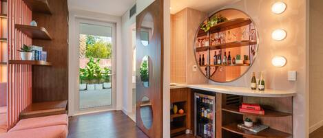 A modern interior with a wooden staircase, a circular shelf with bottles, and a refrigerator stocked with beverages.