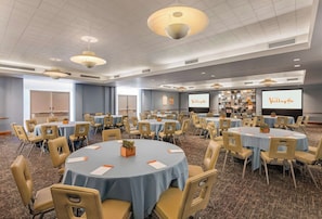 A conference room with multiple tables and chairs, a projector screen, and a carpeted floor. - Hotel Valley Ho (Scottsdale)