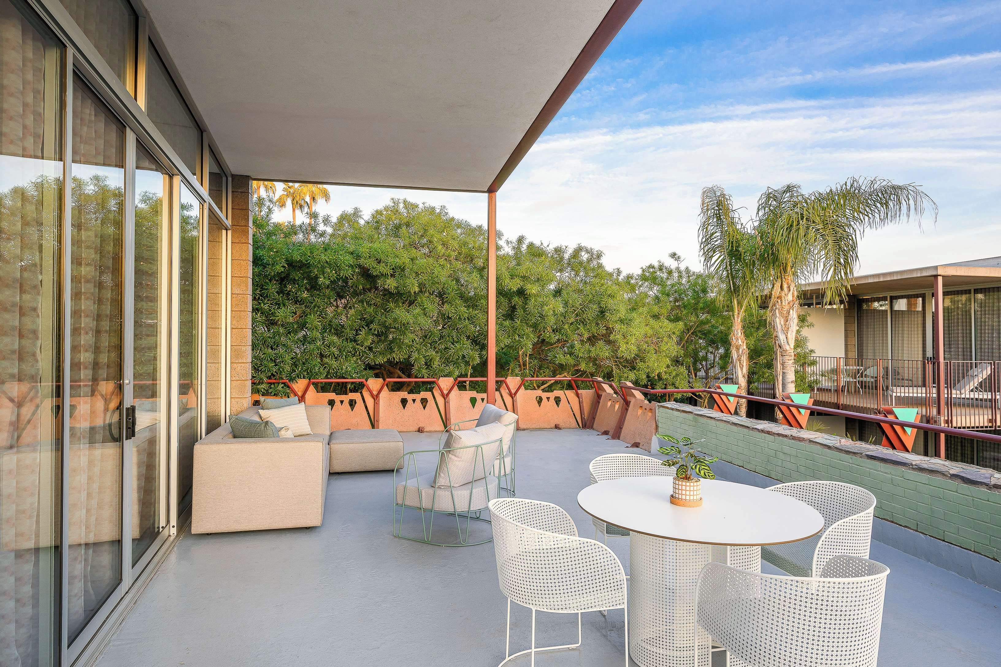 An outdoor patio with a seating area, a table, and chairs.