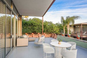 Um pátio externo com área de estar, mesa e cadeiras.