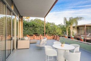 Un patio exterior con una zona de estar, una mesa y sillas.