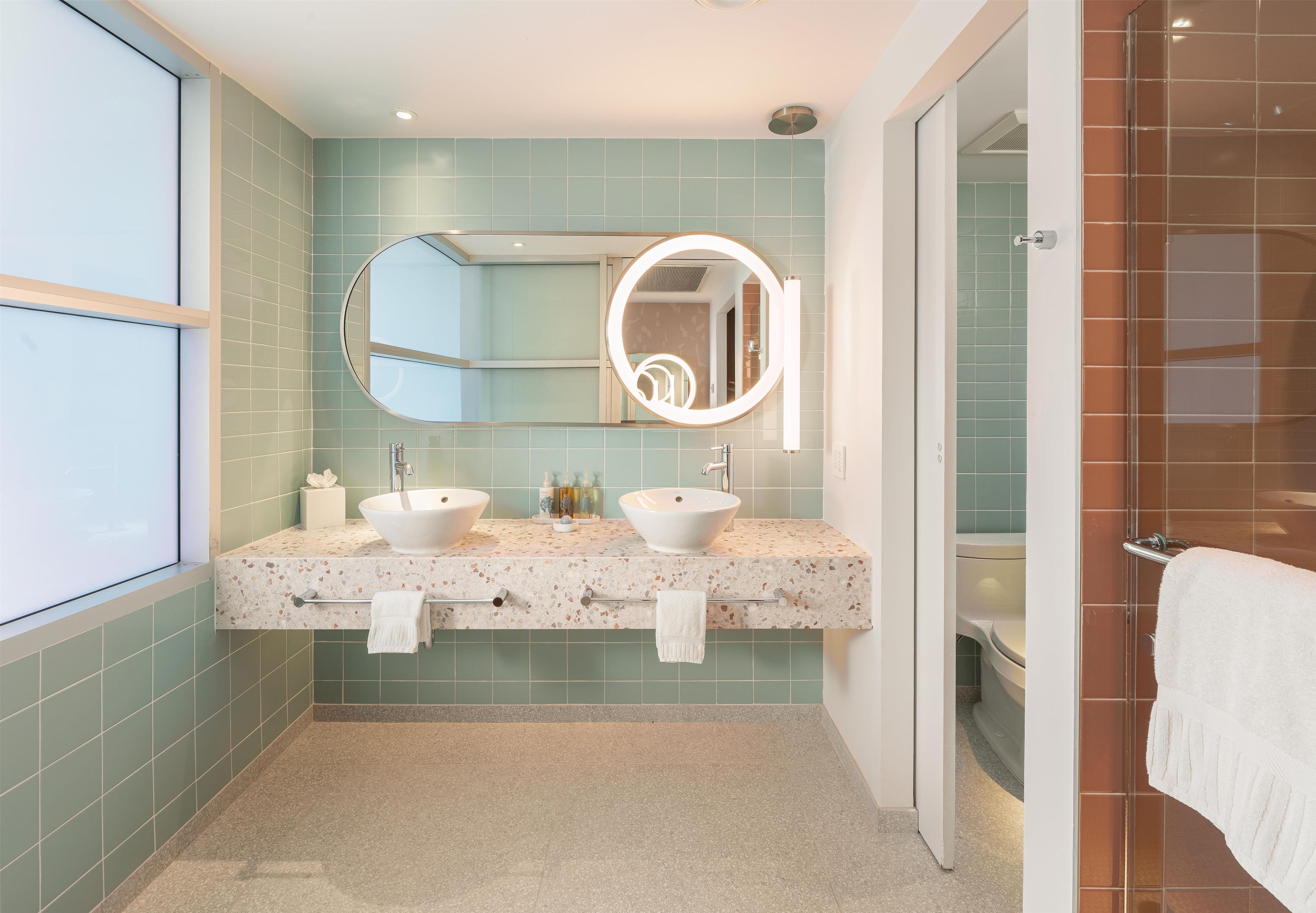 A bathroom with two sinks, a large mirror, and a shower area.