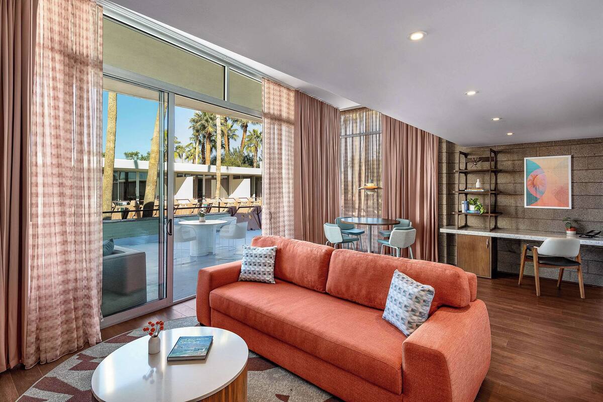 A modern living room with a sofa, coffee table, and a dining area with a table and chairs.