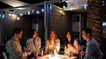 A group of people gathered around a fire pit with a sign above reading "DONN".