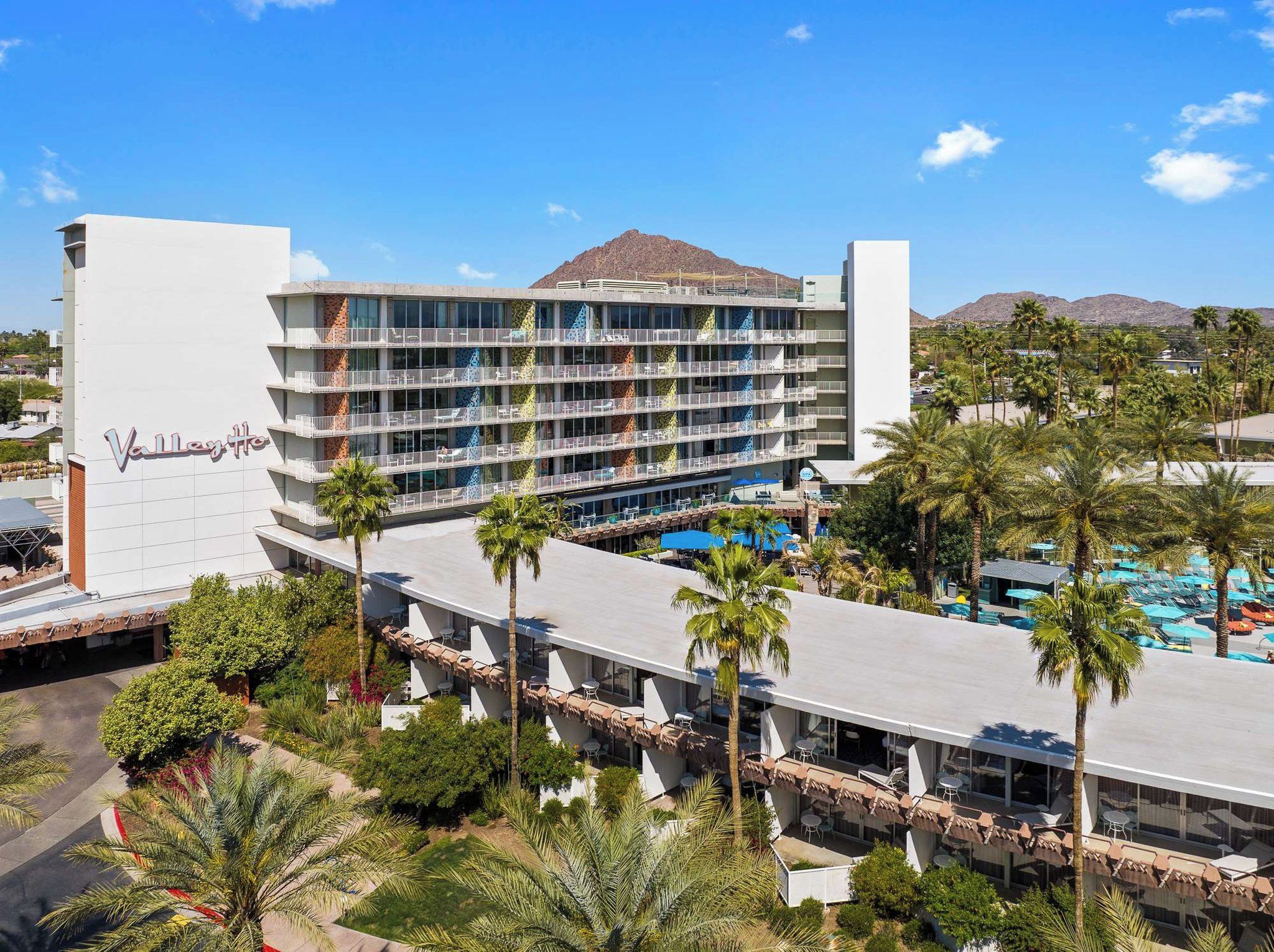A multi-story hotel with a pool area and palm trees.