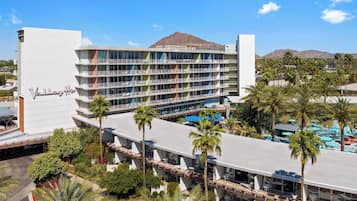 A multi-story hotel with a pool area and palm trees.