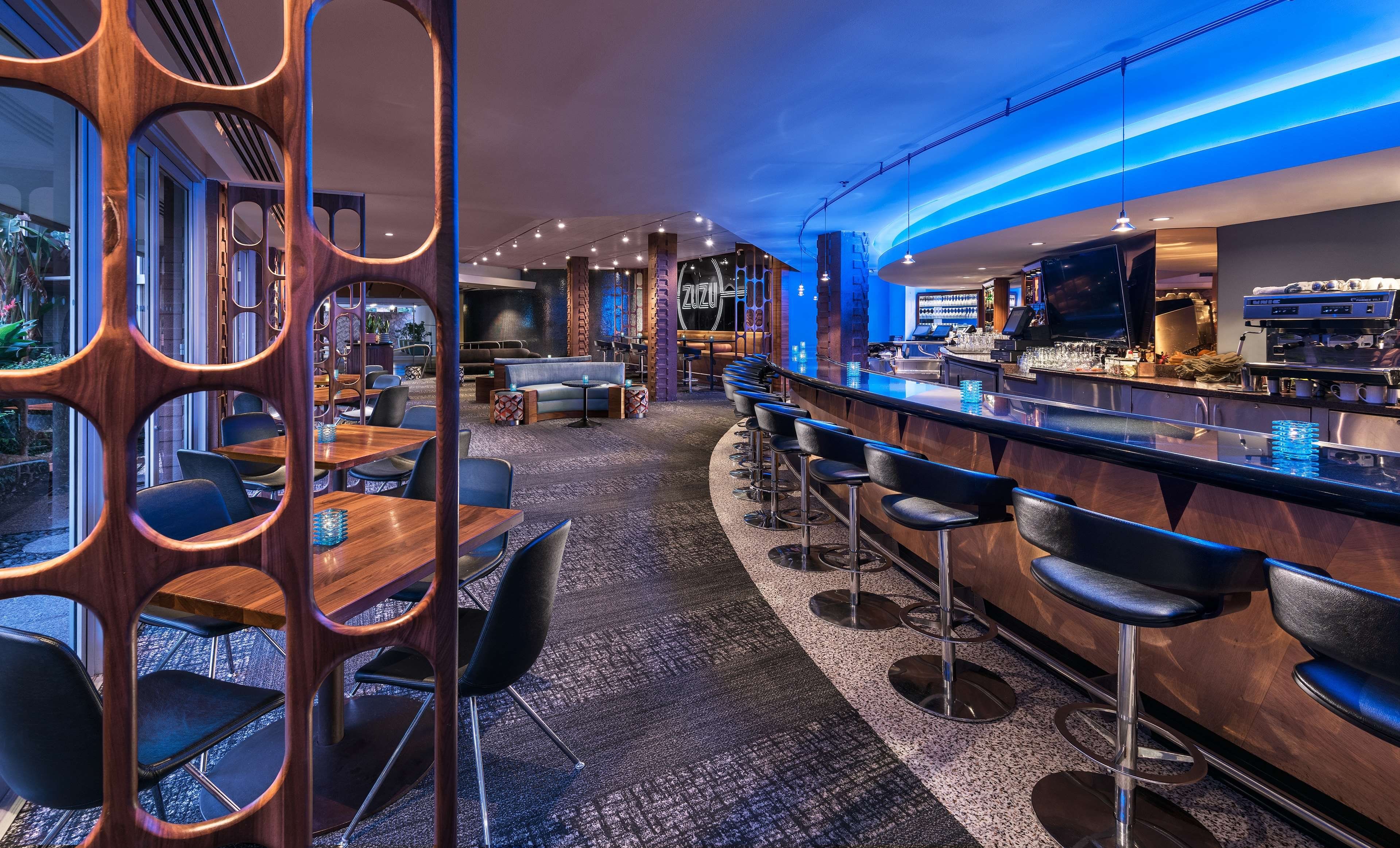 Eine Bar mit einer Theke, Barhocker und einer Sitzgelegenheit mit Tischen und Stühlen.