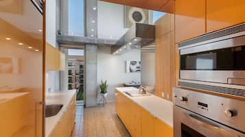 A modern kitchen with stainless steel appliances, a central island, and a view of the building's interior.
