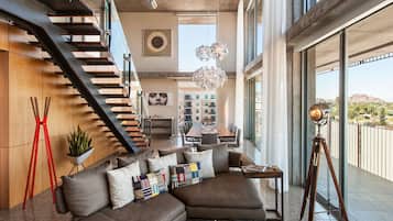 A modern interior with a staircase, a dining area, and a balcony with a tripod.