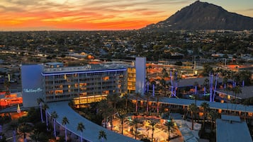 A hotel with multiple floors, a rooftop pool, and a view of a mountain.