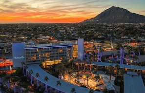 A hotel with multiple floors, a rooftop pool, and a view of a mountain.