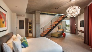 Quarto moderno com uma cama grande, uma escada e vista para o exterior.