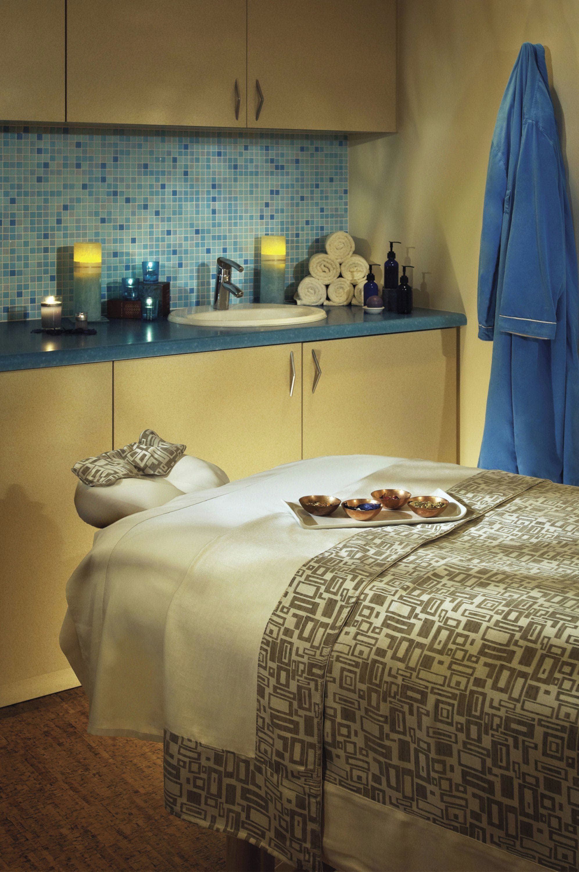 A hotel room with a bed, a bathroom with a sink, and a towel rack.