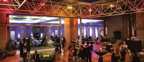 An indoor venue with multiple dining areas, some with round tables and others with square tables, and a variety of seating options including sofas and chairs.