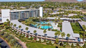 Um resort com uma piscina grande, palmeiras e uma montanha ao fundo.