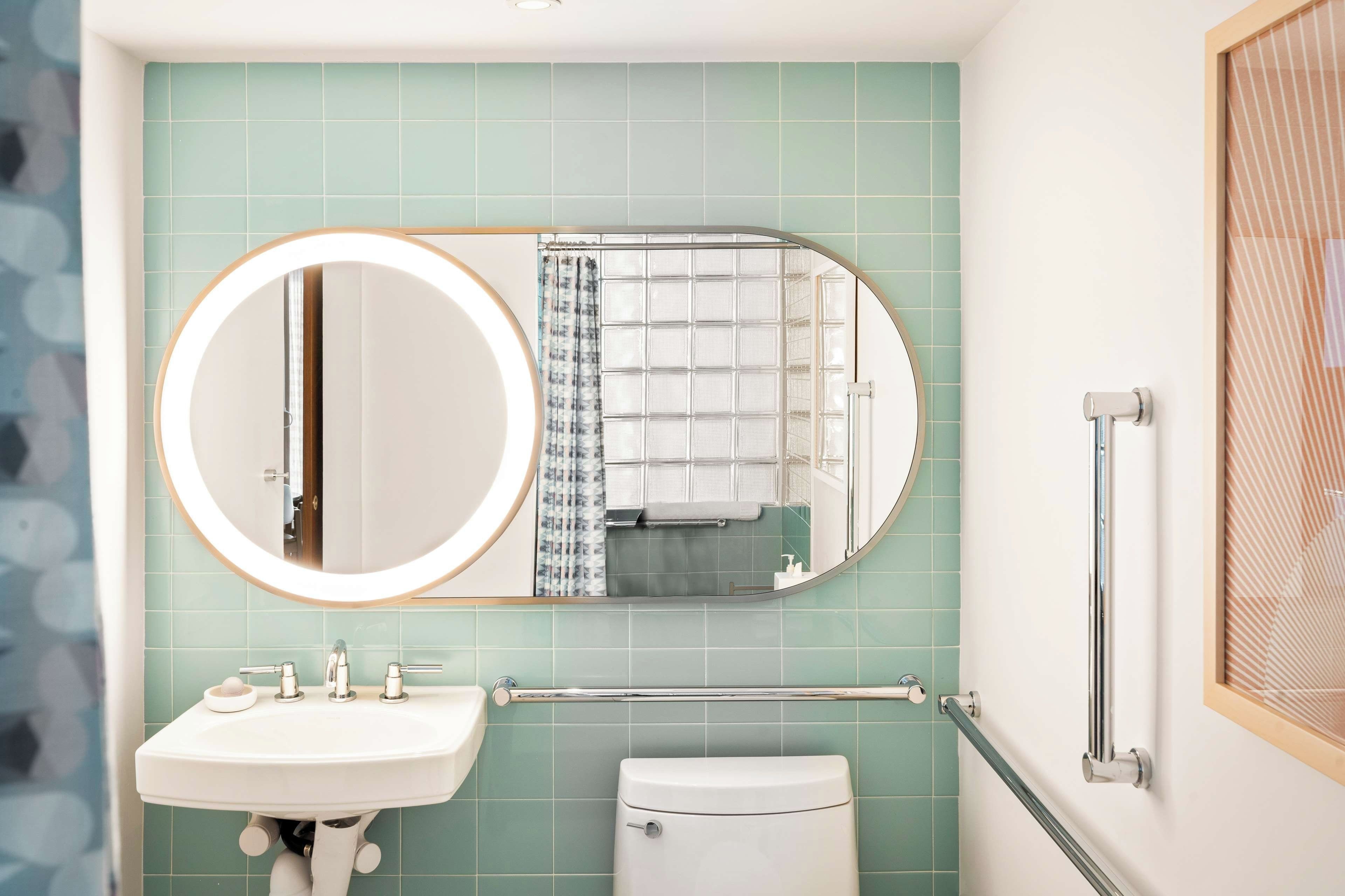 A bathroom with a sink, toilet, and a mirror with a light.