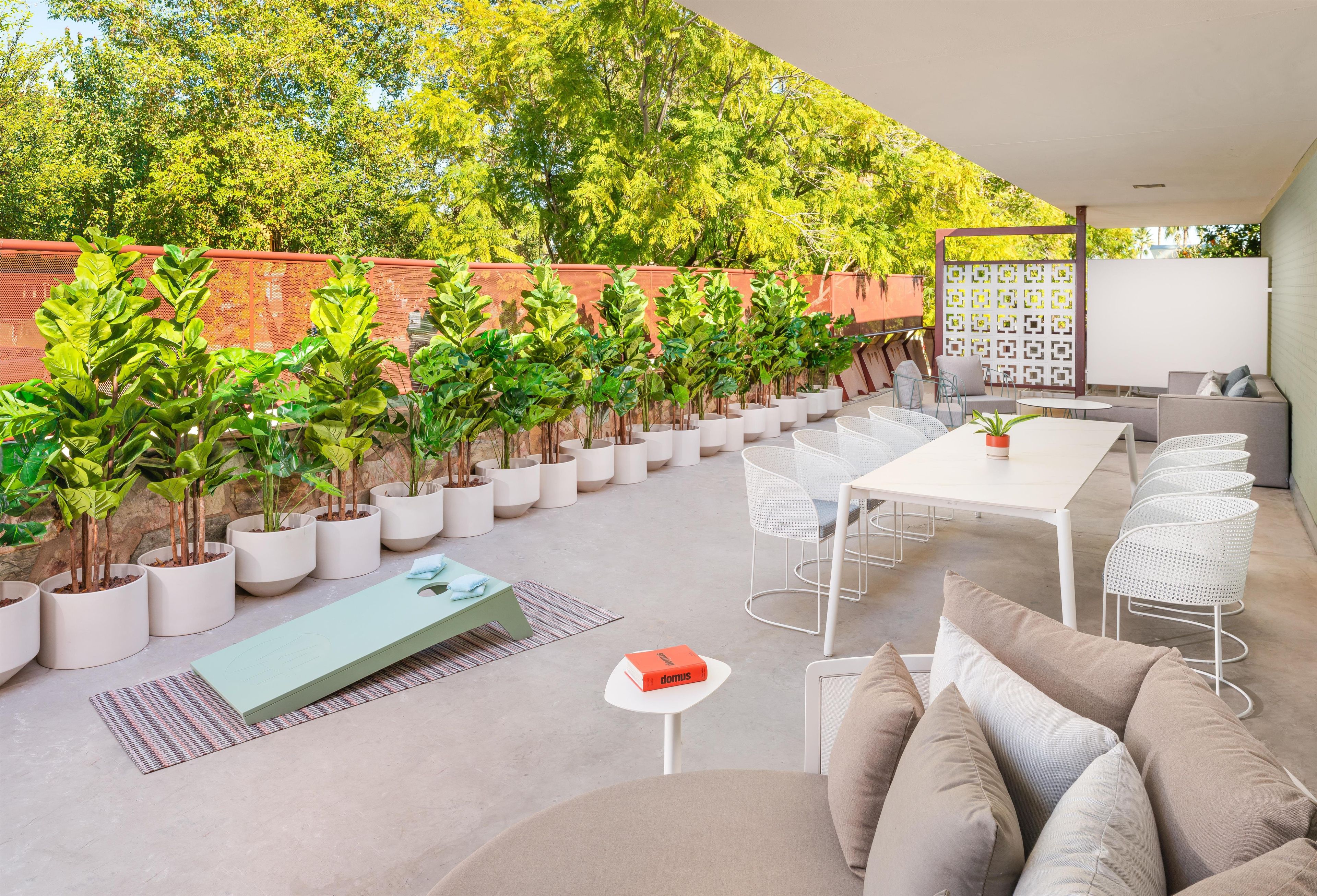 Un espace extérieur aménagé en patio, avec des sièges, des plantes en pot et une table blanche.