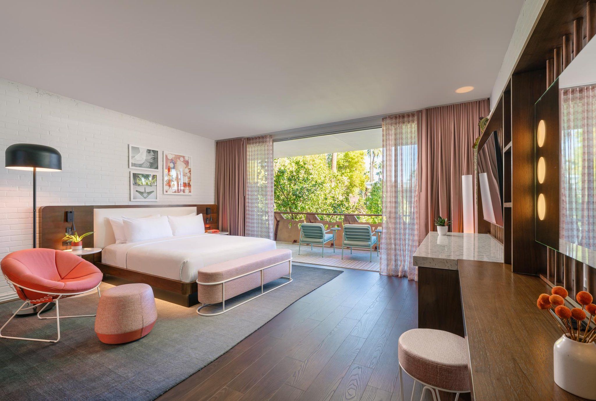 Une chambre d’hôtel moderne dotée d’un lit, d’un coin salon et d’un balcon offrant une vue sur la verdure.
