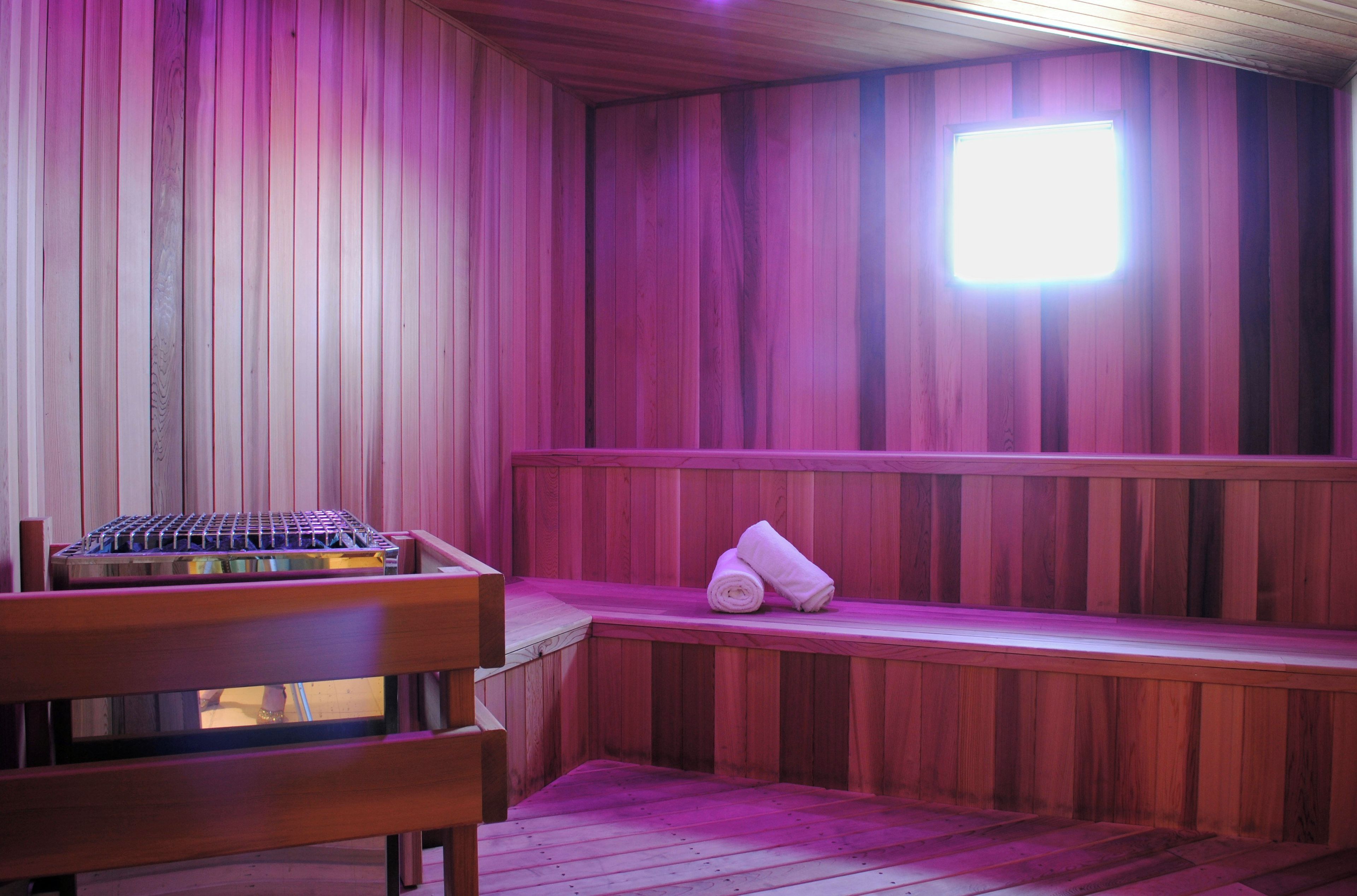 A sauna with wooden walls, a bench, and a towel.