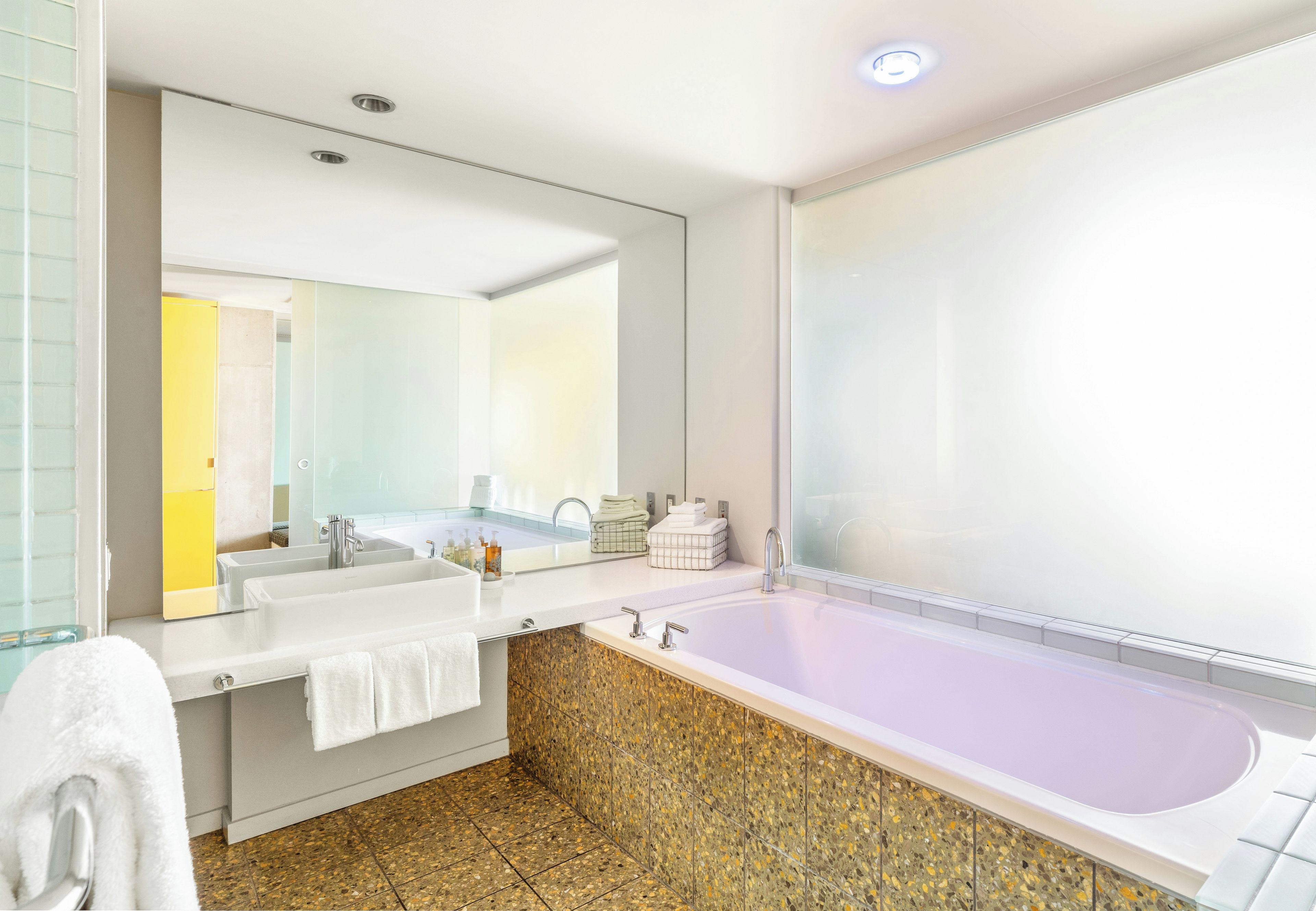 A modern bathroom with two sinks, a large bathtub, and a mirror.