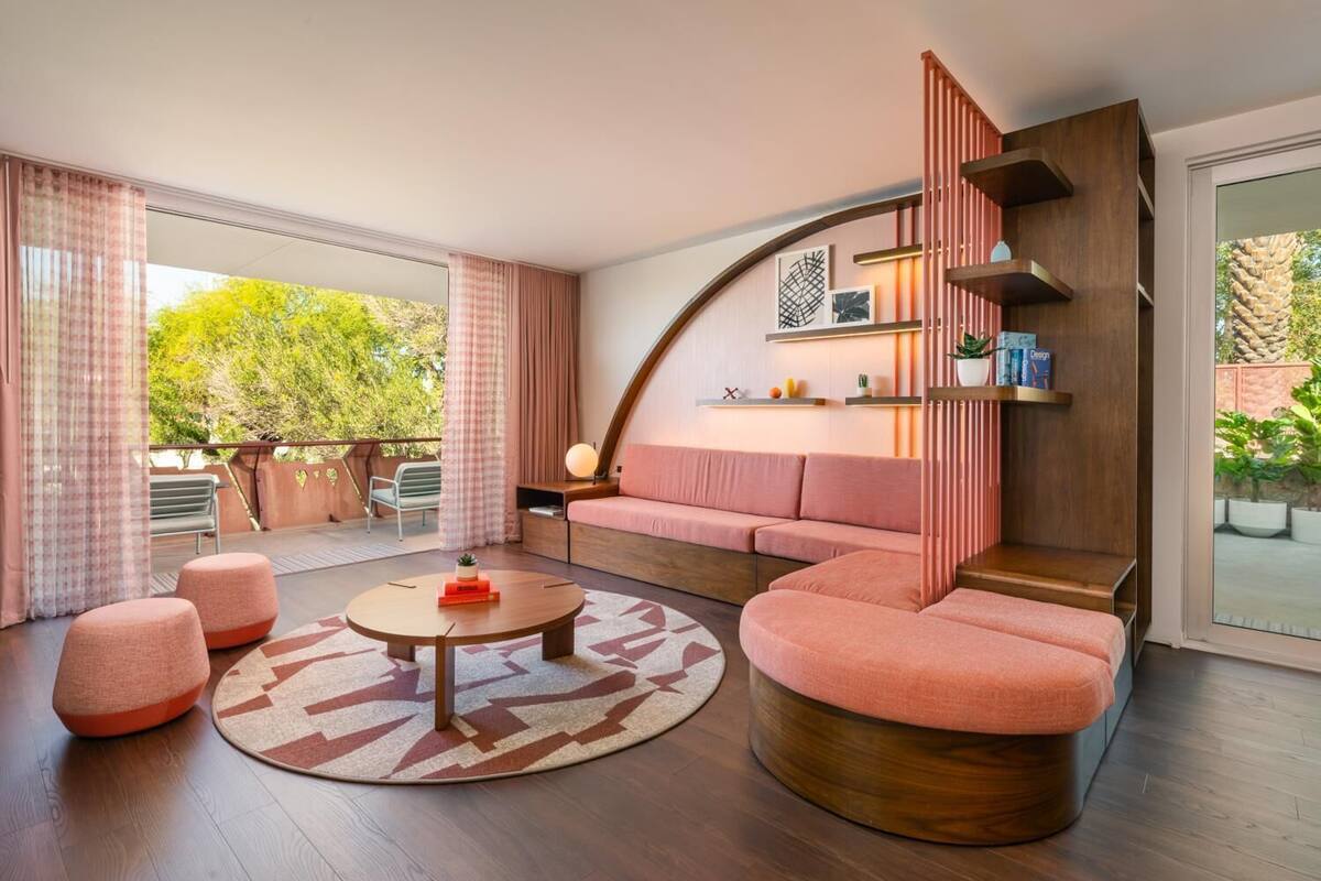 A modern living room with a curved sofa, a round coffee table, and a staircase with a wooden finish.