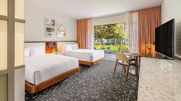 A hotel room with two beds, a desk, a chair, a TV, and a window with curtains.