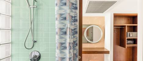 A bathroom with a shower, a toilet, a sink, and a mirror.