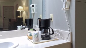 Ein Badezimmer mit Waschbecken, Kaffeemaschine, Haartrockner und Spiegel.