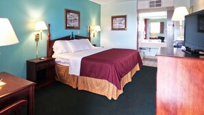Ein Hotelzimmer mit Bett, Nachttischen, Schreibtisch, Stuhl, Fernseher und einem sichtbaren Badezimmer im Hintergrund.