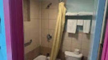 A small bathroom with a bathtub, toilet, and shower.