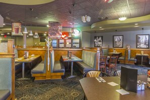 A restaurant with booths, tables, and a patterned carpet. - Quality Inn and Suites (Saskatoon)
