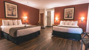Camera d'albergo con due letti, pavimento in legno e opere d'arte incorniciate alle pareti.