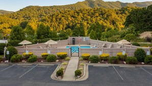 A hotel with a pool, surrounded by well-maintained landscaping and a mountainous backdrop. - Best Western Smoky Mountain Inn (Waynesville)