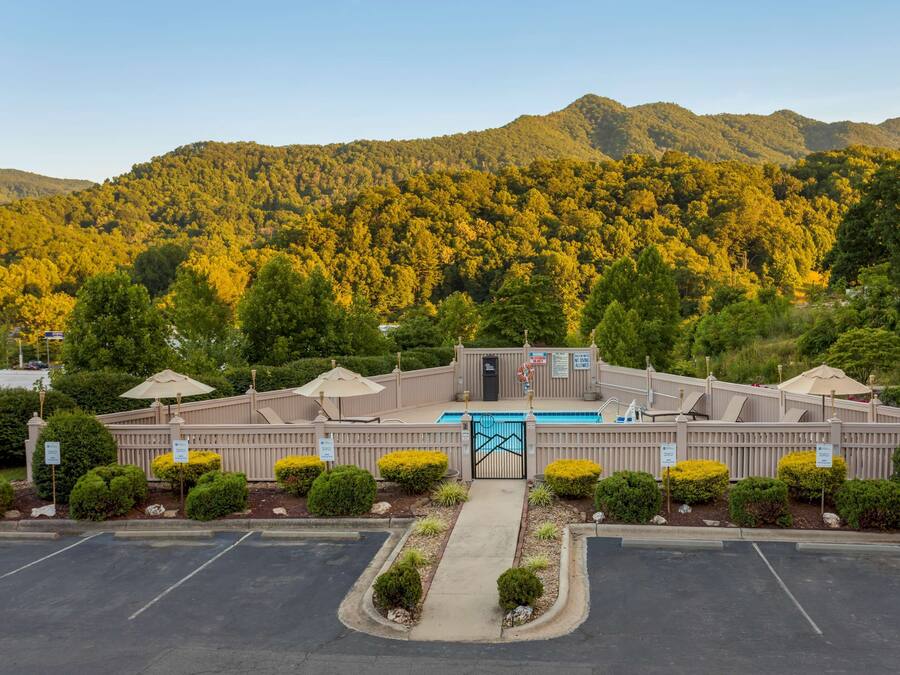 A hotel with a pool, surrounded by well-maintained landscaping and a mountainous backdrop.