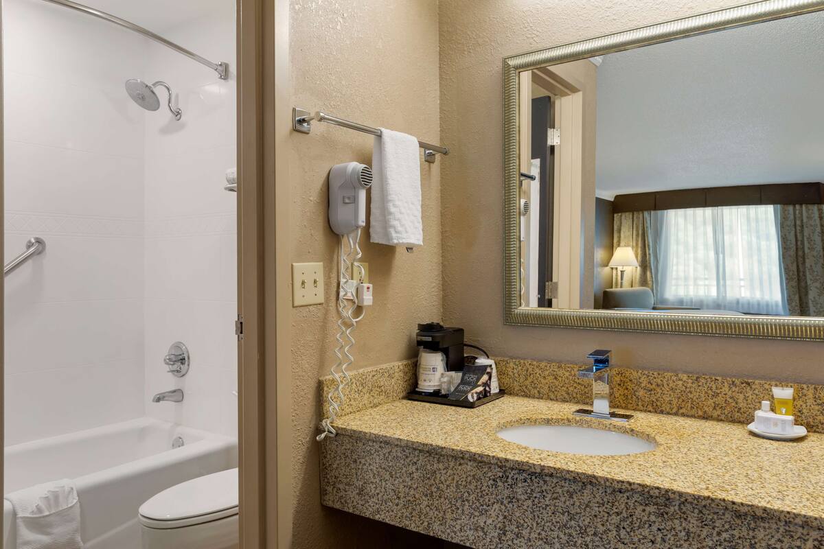 A bathroom with a shower, toilet, sink, and a mirror.