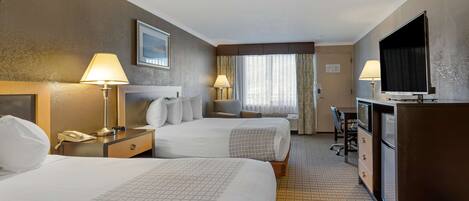 A hotel room with two beds, a desk, a television, and a minibar.