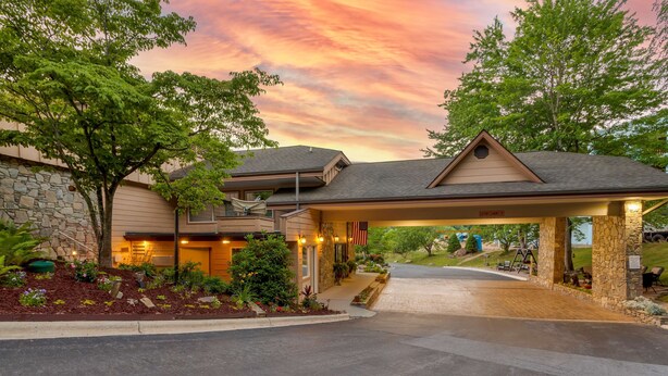 A hotel entrance with a covered driveway, stone facade, and landscaped garden. - Best Western Smoky Mountain Inn (Waynesville)