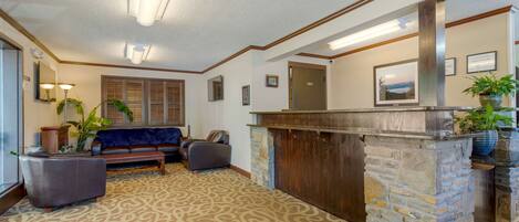 A lobby with a stone reception desk, a blue sofa, and a patterned carpet.