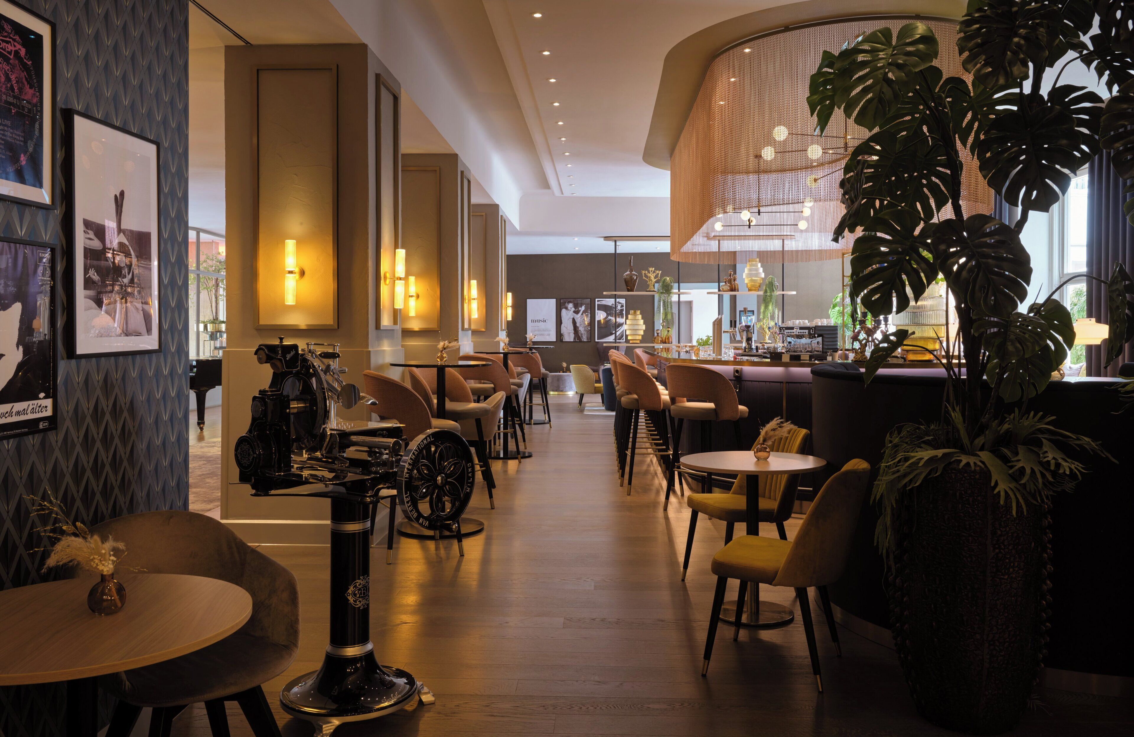 Eine moderne Hotelhalle mit einer zentralen Bar, Sitzbereichen und einer großen Pflanze.