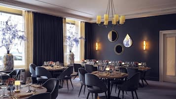 A dining area with round tables, black chairs, and a chandelier.
