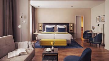 Una habitación de hotel moderna con una cama grande, un sofá, una mesita con un florero y una silla.