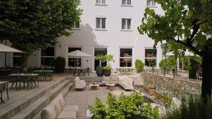 Un patio al aire libre con mobiliario exterior, un sofá y una pared de piedra.