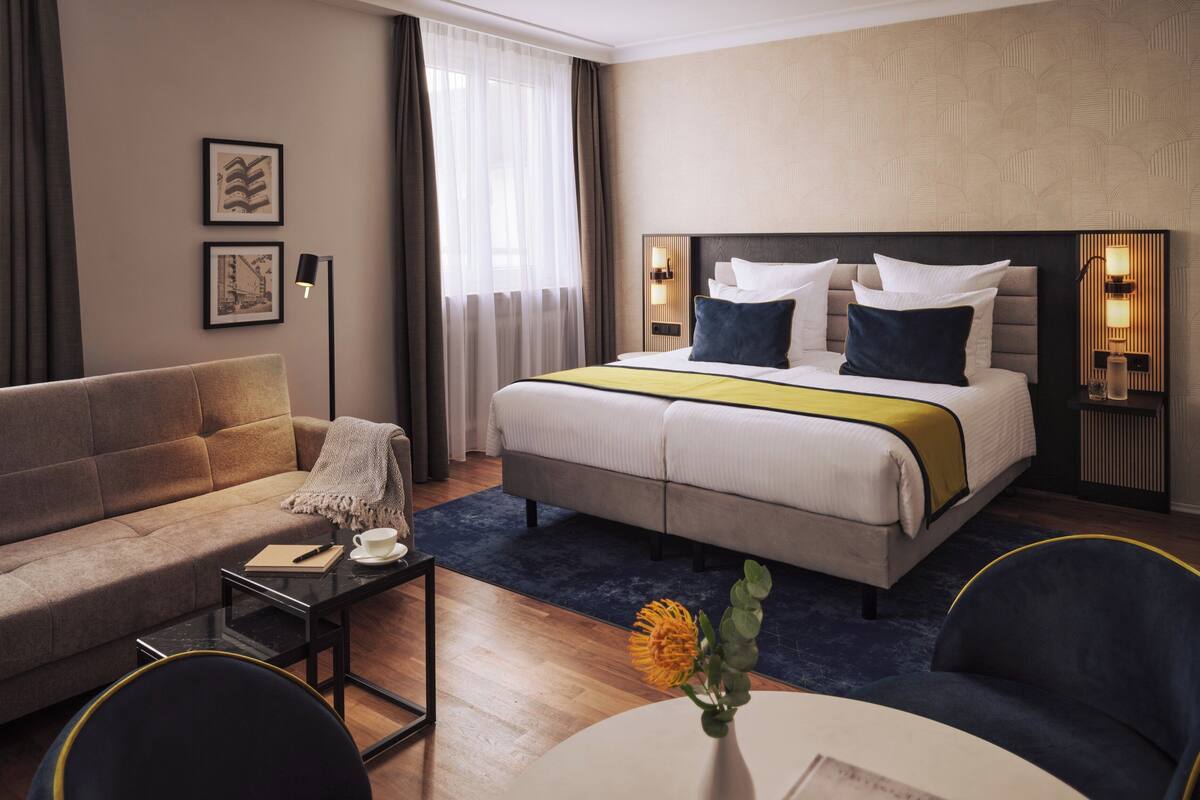 Ein Hotelzimmer mit Bett, einer Couch, einem kleinen Tisch und einem Sessel.