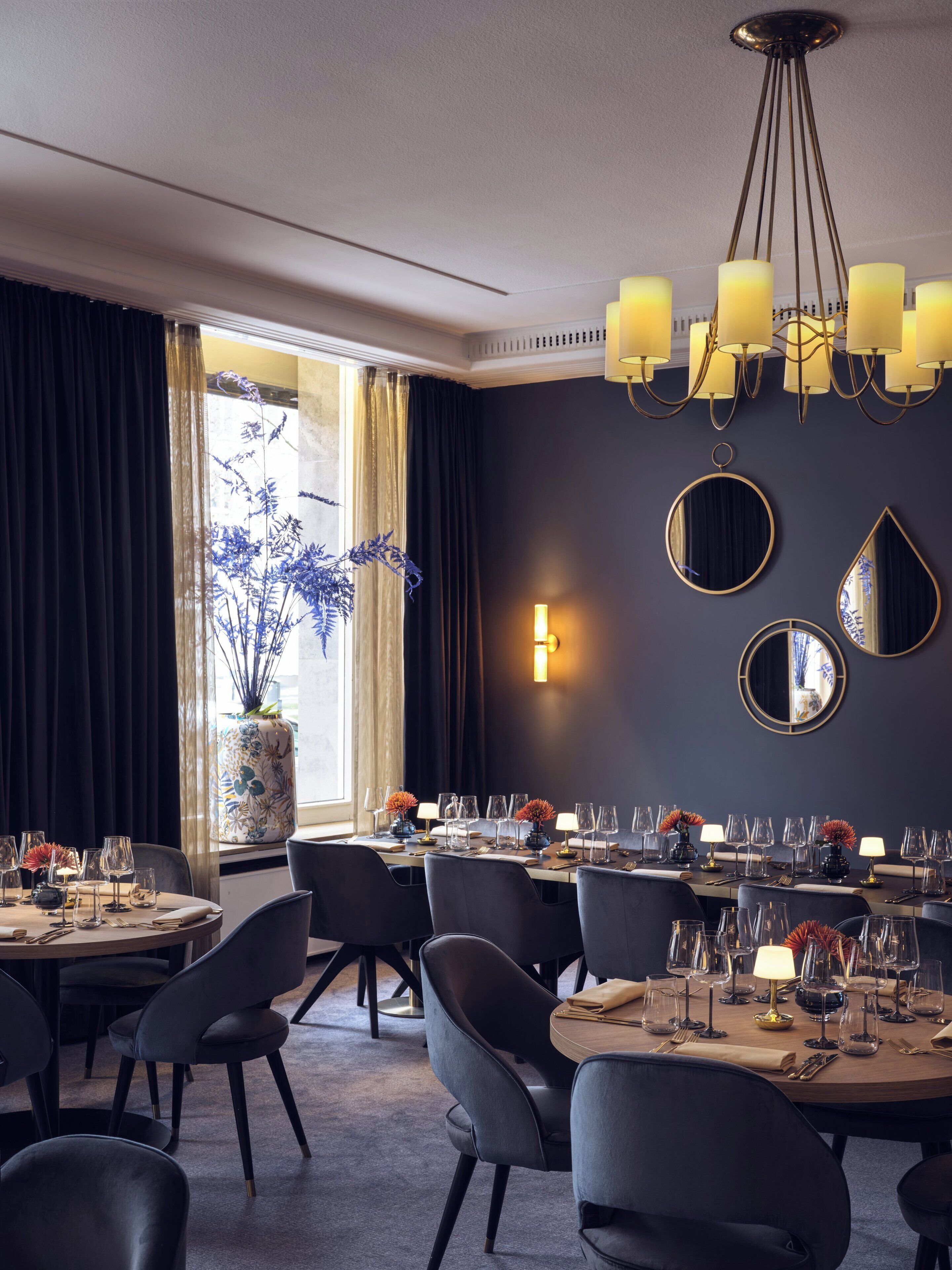 Un comedor con candelabro, espejos redondos y un florero con flores azules.