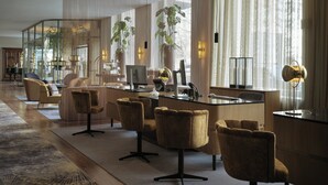 Un moderno vestíbulo de hotel con un mostrador de recepción curvo, asientos cómodos, ventanas amplias y plantas de interior.